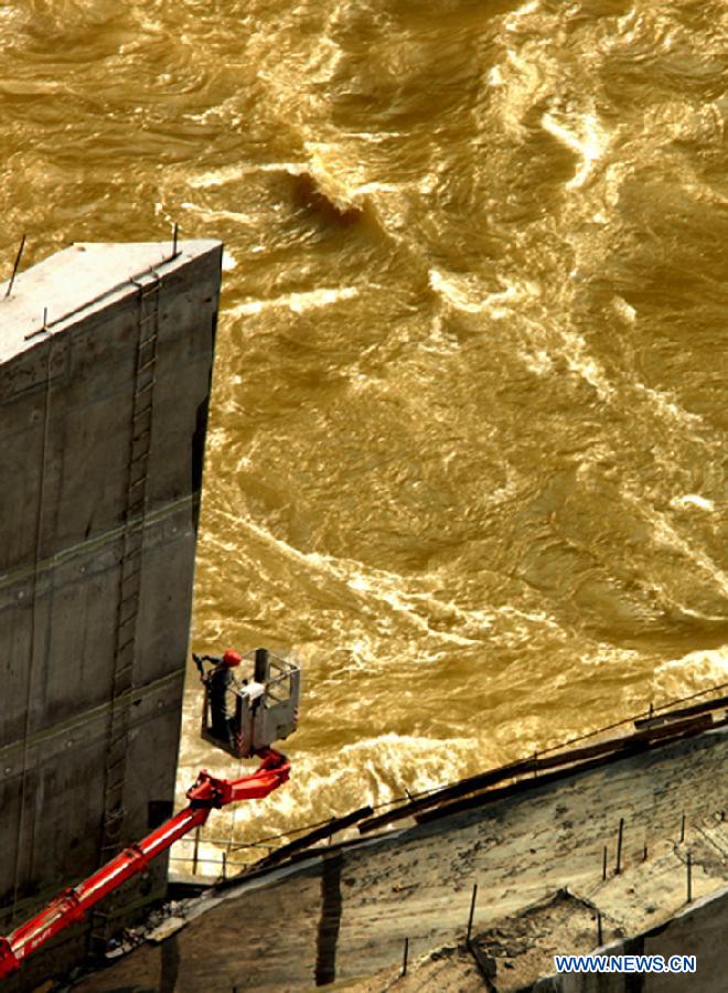 Photo taken on July 8, 2013 shows a worker does construction work of Xiluodu hydropower station, which is located on the lower reach of Jinsha River between Leibo county of Sichuan Province and Yongshan county of Yunnan Province, both in southwest China, above the water of Jinsha River. The first generator unit "13F" went into formal operation on Monday after a three-day trial. The hydropower plant will be the second largest one ranking only second to the Three Gorges when all of its 18 units go into operation in 2014. (Xinhua/Sun Ronggang) 