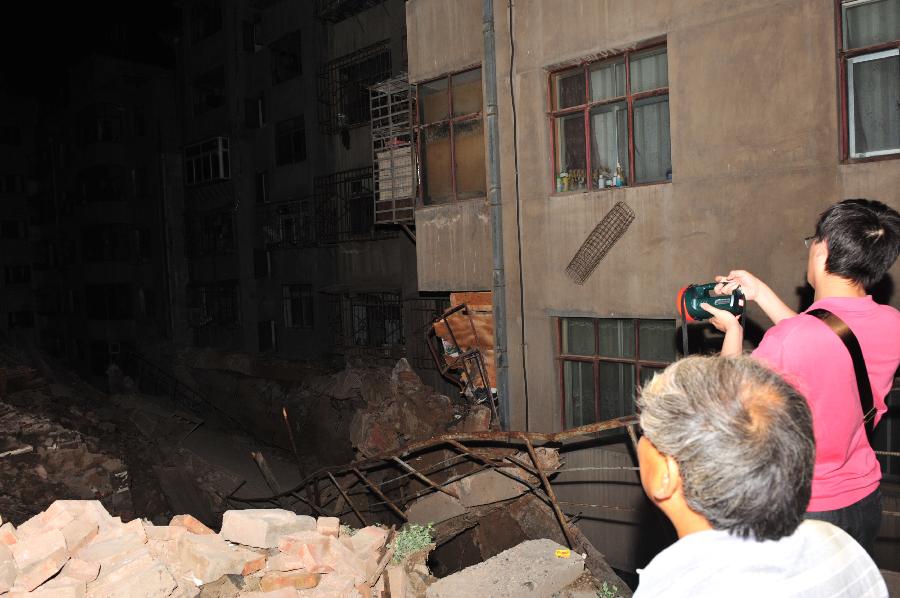 Residents check the landslide site in Chengguan District of Lanzhou City, northwest China's Gansu Province, July 15, 2013. Two landslides happened in Lanzhou on Monday due to the continuous rainfalls, leaving dozens people trapped. The rescue work is underway. (Xinhua/Liang Qiang)