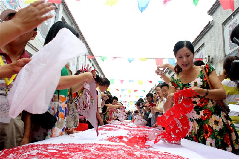 1,000 folk artists work together to create a paper-cut of a Chinese dragon at the 4th Chinese paper-cut art festival in Wei county, Hebei province. The festival was held July 8-10 and featured works from over 360 folk artists around China. (China Daily/Zhou Panpan)