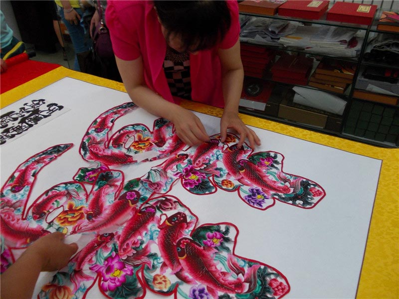 Craftsmen create paper-cut designs at the 4th Chinese paper-cut art festival in Wei county, Hebei province. The festival was held July 8-10 and featured works from over 360 folk artists around China. (China Daily/Tang Zhe)