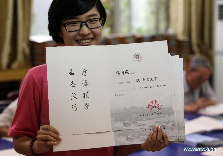 A staff member displays an admission notice written by retired lecturers with writing brush, as a special gift for the newly-recruited students of Shaanxi Normal University, in Xi'an City, northwest China's Shaanxi Province, July 15, 2013. Unlike the printed university adimission notice issued by most of universities in China, Shaanxi Normal University organized more than 20 retired lecturers to write the notice by hand this year. China's annual university recruitment is underway. (Xinhua/Hou Zhi)