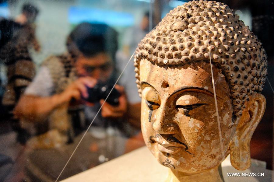 A visitor takes a photo of an exhibit at a public exhibition presenting elaborate antiques of the Xixia Kingdom at the Heilongjiang Provincial Museum in Harbin, capital of northeast China's Heilongjiang Province, July 16, 2013. Xixia (1032-1227), or Western Xia, was a feudal kingdom established by the Tangut ethnic group at the eastern end of the ancient Silk Road. Its territory largely overlapped today's Ningxia Hui Autonomous Region in northwest China. (Xinhua/Wang Song)