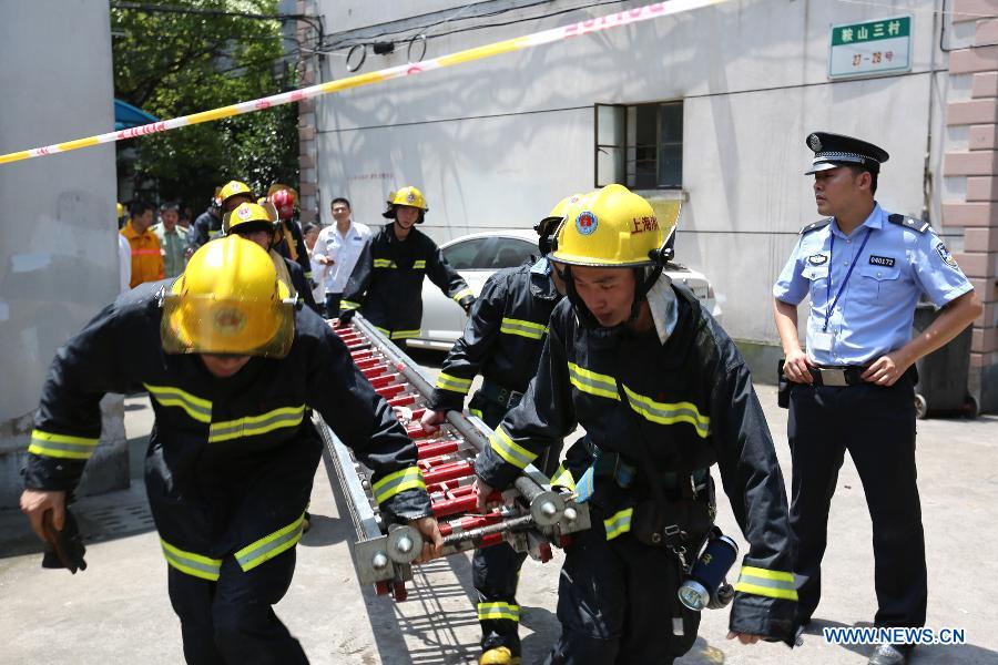 Firemen carry a scaling ladder at the scene of a fire at a residential building at Yangpu District in Shanghai, east China, July 16, 2013. The fire broke out at the five-storey building early Tuesday, leaving two people killed. Local fire department took one hour to douse the fire. (Xinhua/Yang Shichao) 