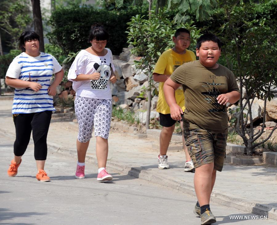 Children go jogging at a summer camp against childhood overweight or obesity in Zhengzhou, capital of central China's Henan Province, July 16, 2013. Coached by doctors and counselors from local children's hospital, 37 children participated in the nearly monthlong camp to lose weight. (Xinhua/Li Bo)  