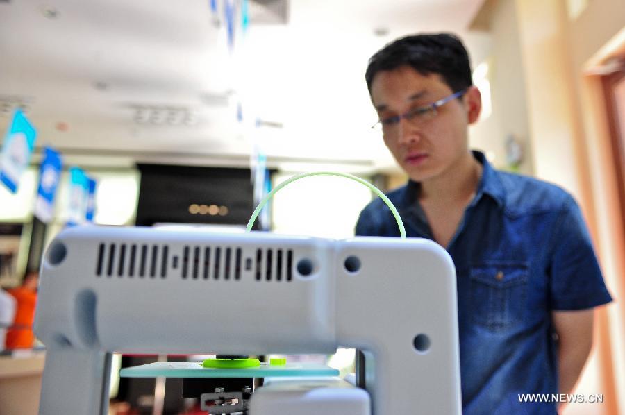 A man watches a plastic cup being made at a 3D-printing experience store in Tianjin, north China, July 16, 2013. (Xinhua/Zhai Jianlan) 