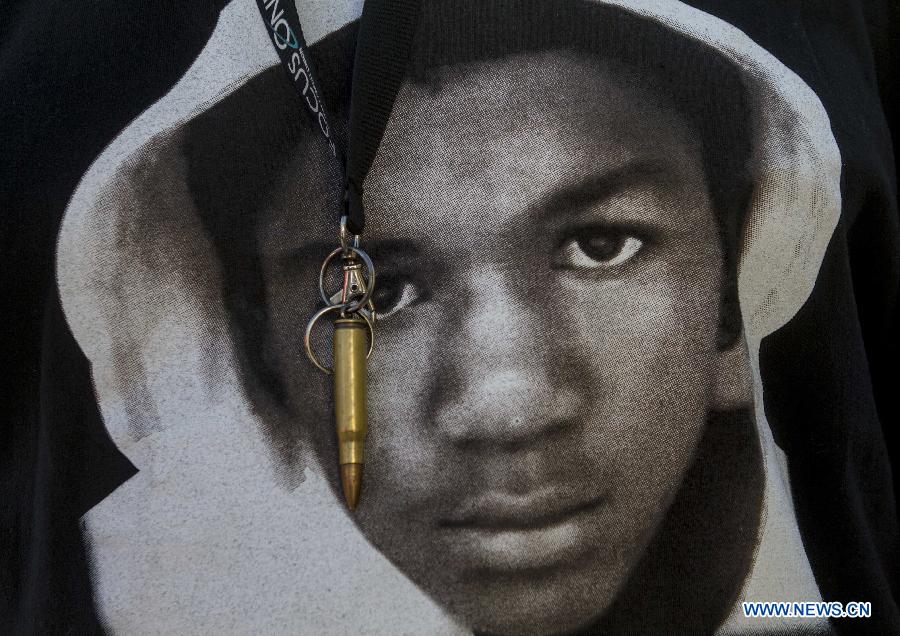 A protester in a T-shirt with the image of Trayvon Martin wears a key chain made of a bullet during a demonstration to protest George Zimmerman's acquittal in the shooting death of Florida teen Trayvon Martin, in Los Angeles, California, July, 15, 2013.A Jury in U.S. state Florida on July 13 acquitted George Zimmerman, who shot and killed Seventeen-year-old African American teenager Trayvon Martin on Feb. 26, 2012, in a case which sparked heated debate on race and guns. (Xinhua/Zhao Hanrong)
