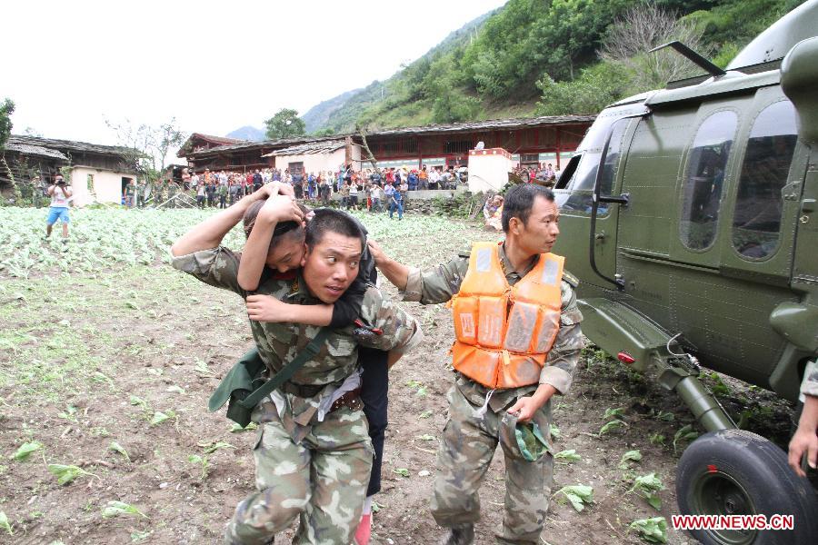 Relief workers transfer an injured child to a helicopter in Caopo Township of Wenchuan County, southwest China's Sichuan Province, July 16, 2013. The People's Liberation Army (PLA) Chengdu Military Area Command has dispatched helicopters to help with relief work in Wenchuan County which has been affected by flooding. An aviation unit dispatched three helicopters with 19 relief workers and 7.5 tonnes of materials in 12 flights to Caopo Township of Wenchuan County, which suffered downpours and mud-rock flows, according to the area command. (Xinhua/Wu Tailiang)