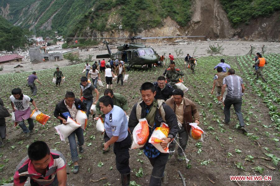 Local residents help relief workers unload disaster-relief supplies from a helicopter in Caopo Township of Wenchuan County, southwest China's Sichuan Province, July 16, 2013. The People's Liberation Army (PLA) Chengdu Military Area Command has dispatched helicopters to help with relief work in Wenchuan County which has been affected by flooding. An aviation unit dispatched three helicopters with 19 relief workers and 7.5 tonnes of materials in 12 flights to Caopo Township of Wenchuan County, which suffered downpours and mud-rock flows, according to the area command. (Xinhua/Wu Tailiang)