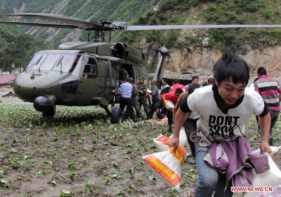 Local residents carry disaster-relief supplies from a helicopter in Caopo Township of Wenchuan County, southwest China's Sichuan Province, July 16, 2013. The People's Liberation Army (PLA) Chengdu Military Area Command has dispatched helicopters to help with relief work in Wenchuan County which has been affected by flooding. An aviation unit dispatched three helicopters with 19 relief workers and 7.5 tonnes of materials in 12 flights to Caopo Township of Wenchuan County, which suffered downpours and mud-rock flows, according to the area command. (Xinhua/Wu Yongbin)