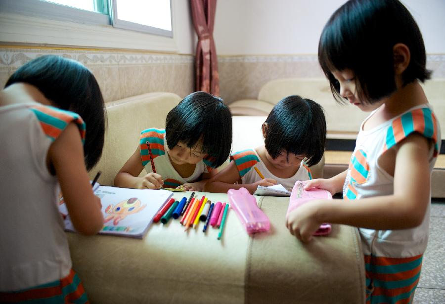 The quadruplet sisters draw pictures at home.(Xinhua/Hu Chenhuan) 