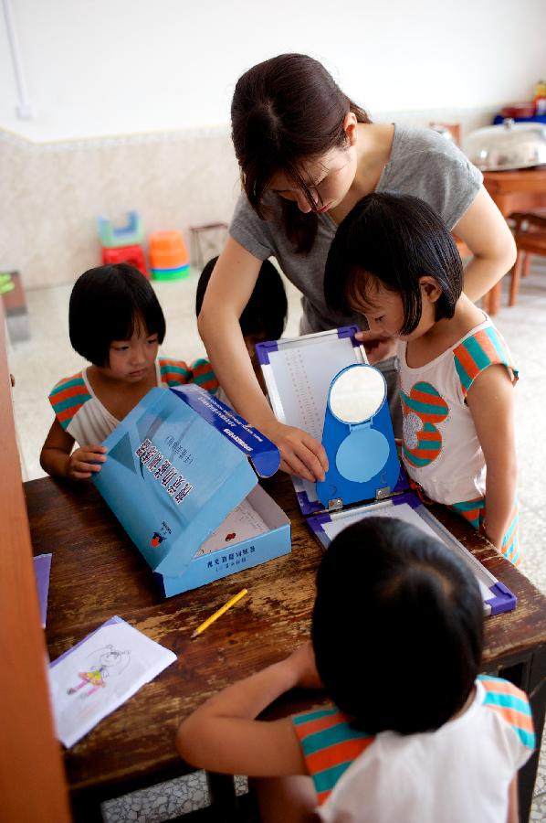 Zhu Yanhong checks her third girl’s eyesight on June 30, 2013. (Xinhua/Hu Chenhuan) 