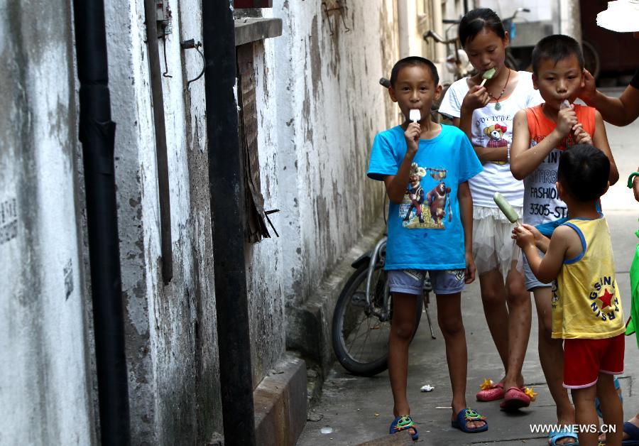 Children have ice cream in an alley in the Baodai residential area of Yuyuan Street, east China's Shanghai, July 16, 2013. Shanghai suffers from high temperature in recent days. (Xinhua/Pei Xin) 