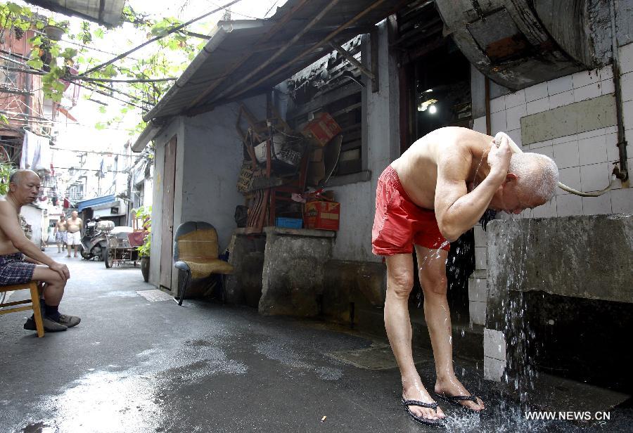 An old man takes a shower outside his home in the Baodai residential area of Yuyuan Street, east China's Shanghai, July 16, 2013. Shanghai suffers from high temperature in recent days. (Xinhua/Pei Xin) 