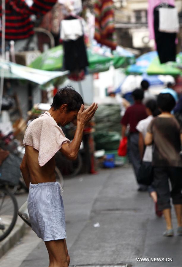 A man wipes sweat on the head as he walks out of his home in the Baodai residential area of Yuyuan Street, east China's Shanghai, July 16, 2013. Shanghai suffers from high temperature in recent days. (Xinhua/Pei Xin) 