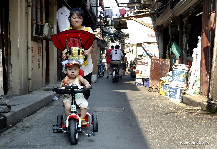 A woman pushes a kid in children's cart in the Baodai residential area of Yuyuan Street, east China's Shanghai, July 16, 2013. Shanghai suffers from high temperature in recent days. (Xinhua/Pei Xin) 