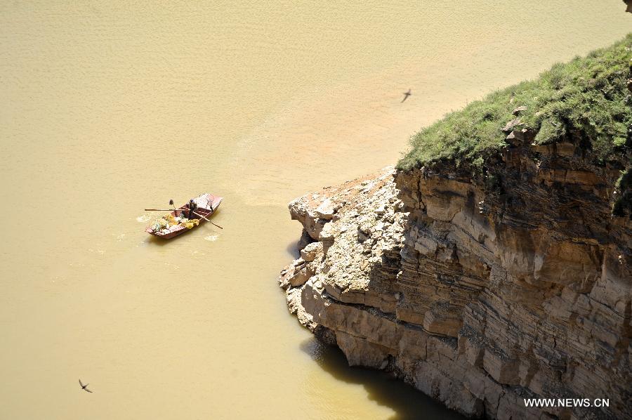 A villager boats on the Yellow River in Laoniuwan in Hohhot, north China's Inner Mongolia Autonomous Region, July 16, 2013. The Great Wall meets the Yellow River in Laoniuwan, which was turned into a geopark in December of 2012 and opened to the public on July 16, 2013.(Xinhua/Jin Yu)