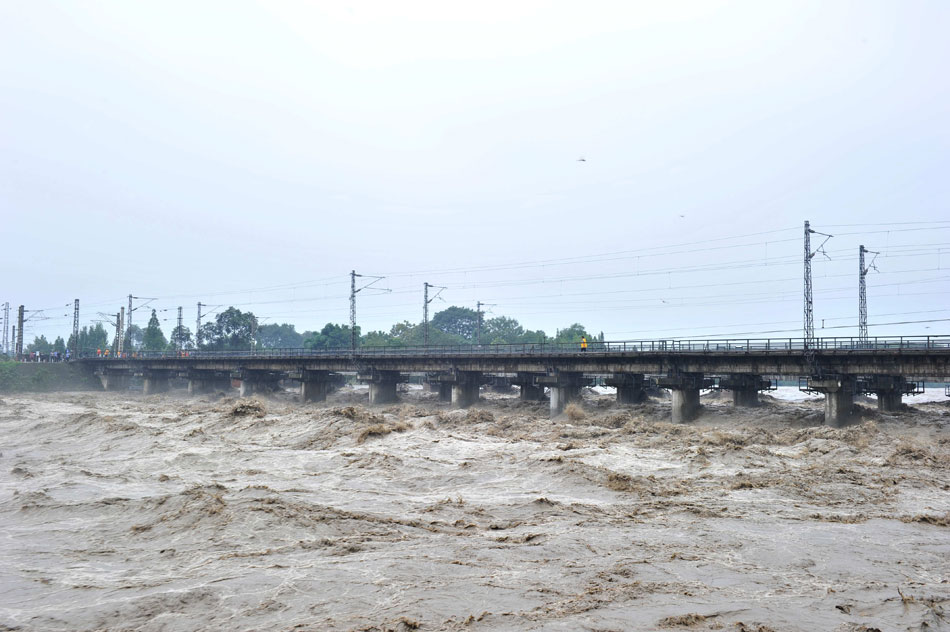 An iron barge is pushed by strong flood and then crashes into a railway bridge in southwest China’s Chengdu city, July 9, 2013. (Xinhua/Wang Zhengwei)