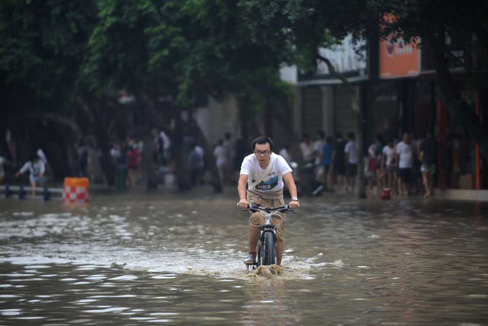 A man rides in a submerged street after days of rainstorm in southwest China’s Chengdu city, July 9, 2013. (Xinhua/Xue Yubin)