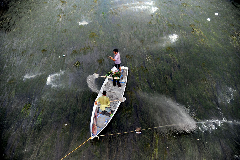 Staff cleans out weed in the canal in Shenyang, capital city of Liaoning province on July 11, 2013. On the same day, Shenyang city canal landscape management office carried out water weed cleaning along the 50-km-long canal so as to improve its ecological environment. (Xinhua/ Zhang Wenkui)