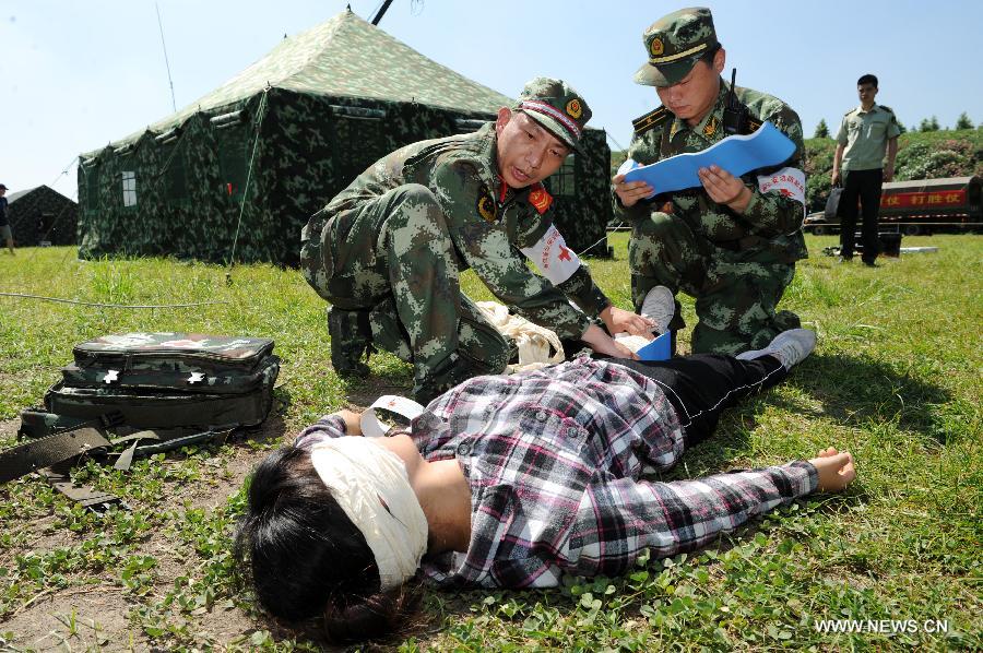Soldiers wrap an injuered man in a rescue drill held in Hangzhou of east China's Zhejiang Province, July 17, 2013. The emergency drill was held on Wednesday to improve the reaction capability against typhoon. (Xinhua/Ju Huangzong) 