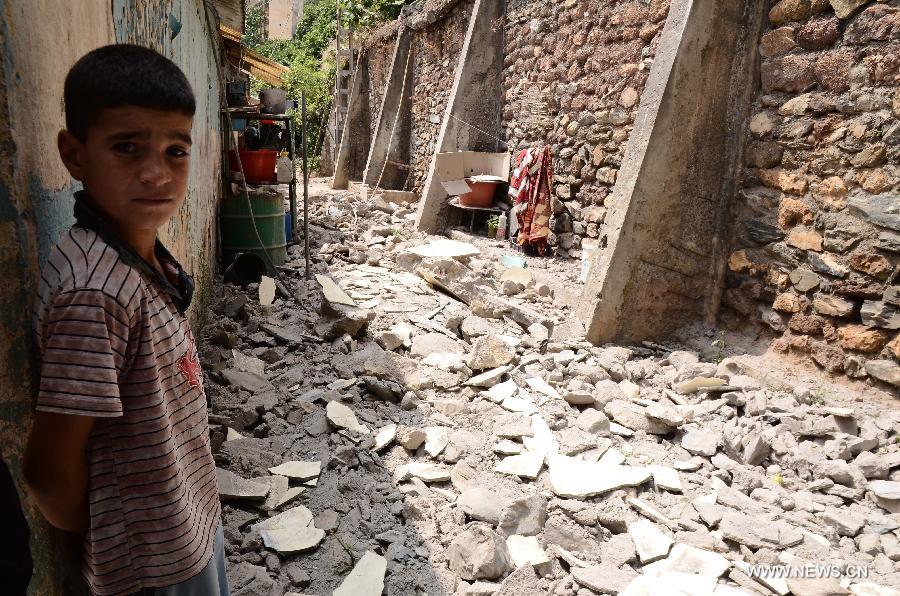 A boy stands in front of some house debris dropped in the earthquake shaking the locality of Hammam Melouene, in the province of Blida, 45 km south of Algiers, in Algeria, on July 17, 2013. An earthquake measuring 5.1 on the Richter scale on Wednesday hit Algeria's northern province of Blida, some 45 km south of capital Algiers, injuring 11 people, official APS news agency reported. (Xinhua/Mohamed Kadri)