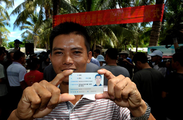 Liang Feng receives his residence permit card in Sansha city, July 17, 2013. (Photo/Xinhua)