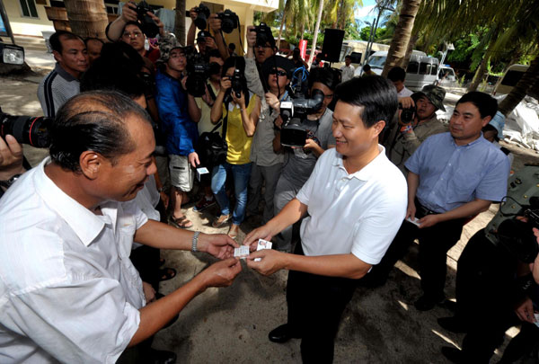 Feng Wenhai, center, vice-mayor of Sansha city, hands out residence permit cards to residents, July 17, 2013. (Photo/Xinhua)