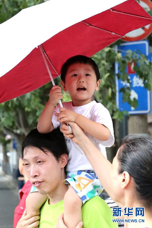 A boy holds a sunshade on a street of Shanghai on July 15, 2013. The temperature reached 35 degrees Celsius on the day. The weather station of Shanghai issued a yellow warning of high temperature. (Xinhua/Liu Dawei)