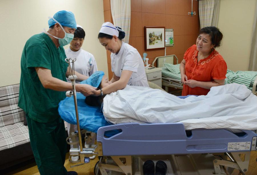 Qiu, the first pregnant woman in the world infected with H7N9 bird flu, prepares to get into the operating room to give a caesarean birth in the No.1 People's Hospital of Zhenjiang, east China's Jiangsu Province, July 17, 2013. Diagnosed as H7N9 bird flu patient on April 8, 2013, Qiu gave birth to a girl here on Wednesday. (Xinhua/Wang Cheng) 