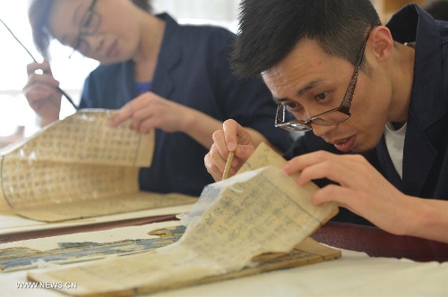 Students mend the ancient torn books at Tianjin Library in North China's Tianjin Municipality, July 17, 2013. Tianjin Library recently launched the first session of the "Ancient Book Restoration Skill and Work Management Course" facing the urgent situation many volumes of ancient endangered books need to be restored. (Xinhua) 