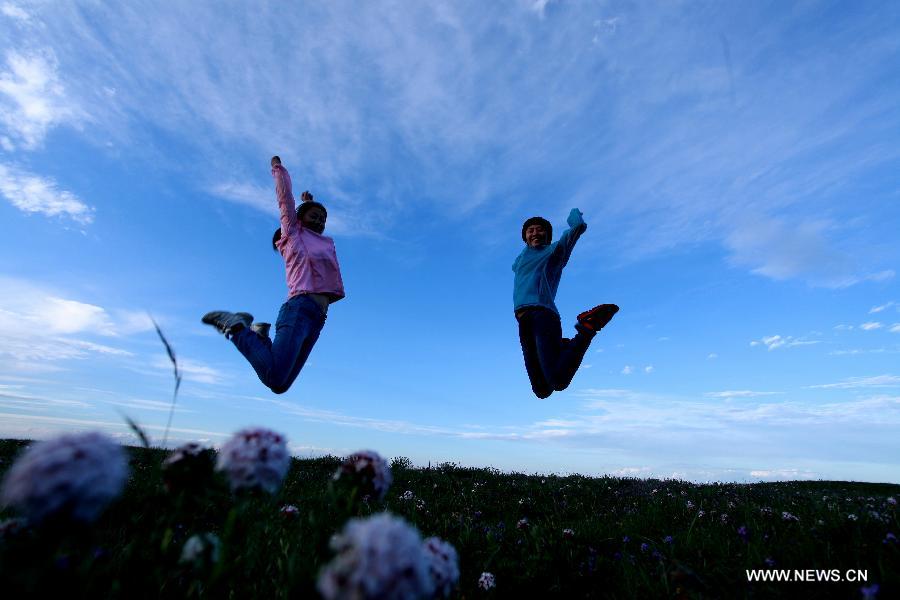 Two tourists play beside the Qinghai Lake in northwest China's Qinghai Province, July 15, 2013. Qinghai Plateau attacts many tourists for its brisk weather in summer. (Xinhua/Yang Shoude)