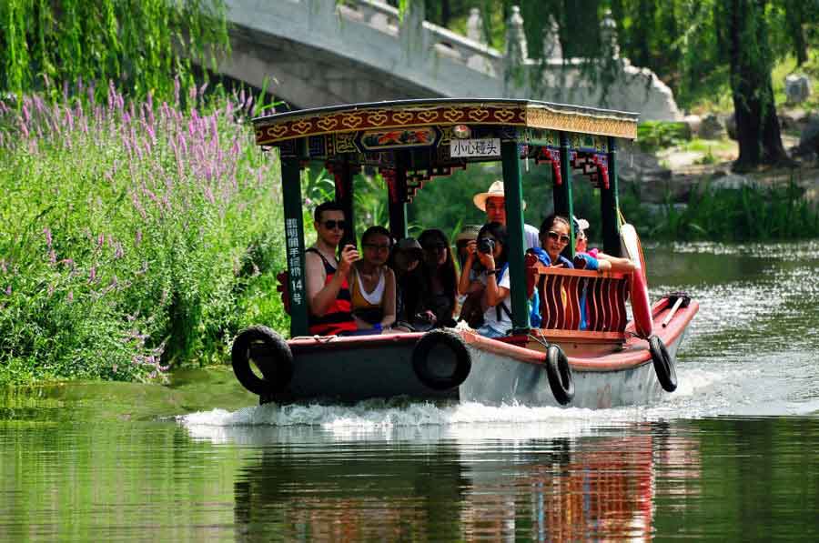 Both foreign and Chinese tourists are fascinated by the elegant lotus flowers at Yuanmingyuan Park. Tourists enjoy the picturesque view aboard a boat on July 16, 2013. (Photo: CRIENGLISH.com/ Song Xiaofeng)