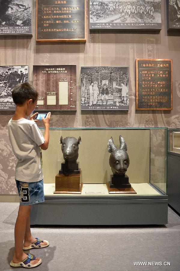 A child takes photos of the bronze heads of a rat and a rabbit, donated by the Pinault family of France in April, at the National Museum of China in Beijing, capital of China, July 18, 2013. The two pieces of relics were among 12 animal head sculptures that formed a zodiac water clock previously stood at Yuanmingyuan, or the Old Summer Palace, in northwest Beijing. They were looted by Anglo-French Allied forces during the Second Opium War in 1860. (Xinhua/Li Xin)