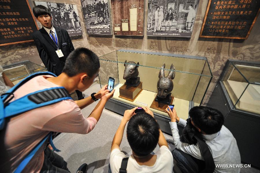 Visitors take photos of the bronze heads of a rat and a rabbit, donated by the Pinault family of France in April, at the National Museum of China in Beijing, capital of China, July 18, 2013. The two pieces of relics were among 12 animal head sculptures that formed a zodiac water clock previously stood at Yuanmingyuan, or the Old Summer Palace, in northwest Beijing. They were looted by Anglo-French Allied forces during the Second Opium War in 1860. (Xinhua/Li Xin)