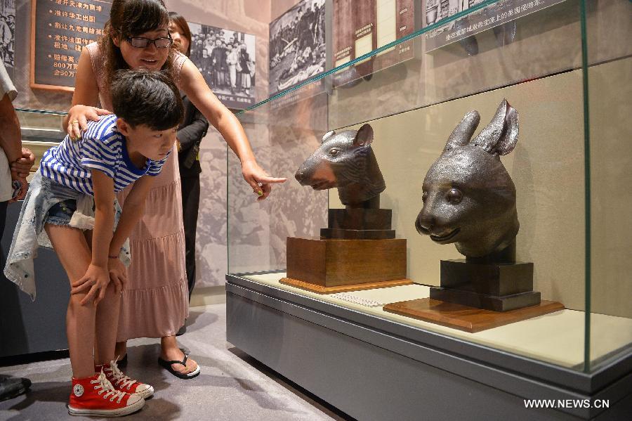 Visitors view the bronze heads of a rat and a rabbit, donated by the Pinault family of France in April, at the National Museum of China in Beijing, capital of China, July 18, 2013. The two pieces of relics were among 12 animal head sculptures that formed a zodiac water clock previously stood at Yuanmingyuan, or the Old Summer Palace, in northwest Beijing. They were looted by Anglo-French Allied forces during the Second Opium War in 1860. (Xinhua/Li Xin)