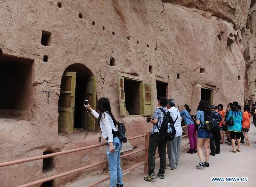Tourists visit the Bingling Temple Grottoes in Yongjing County, northwest China's Gansu Province, July 17, 2013. Listed as part of the ancient Silk Road for the World Heritage candidate, the grottoes will be reviewed by experts from U.N. Educational, Scientific and Cultural Organization after renovation of a giant Buddha statue dating back more than 1,000 years to the Tang Dynasty was completed lately. Bingling Temple Grottoes, filled with Buddhist statues, stupas and murals, were a work in progress between the 4th and 10th centuries. (Xinhua/Nie Jianjiang)