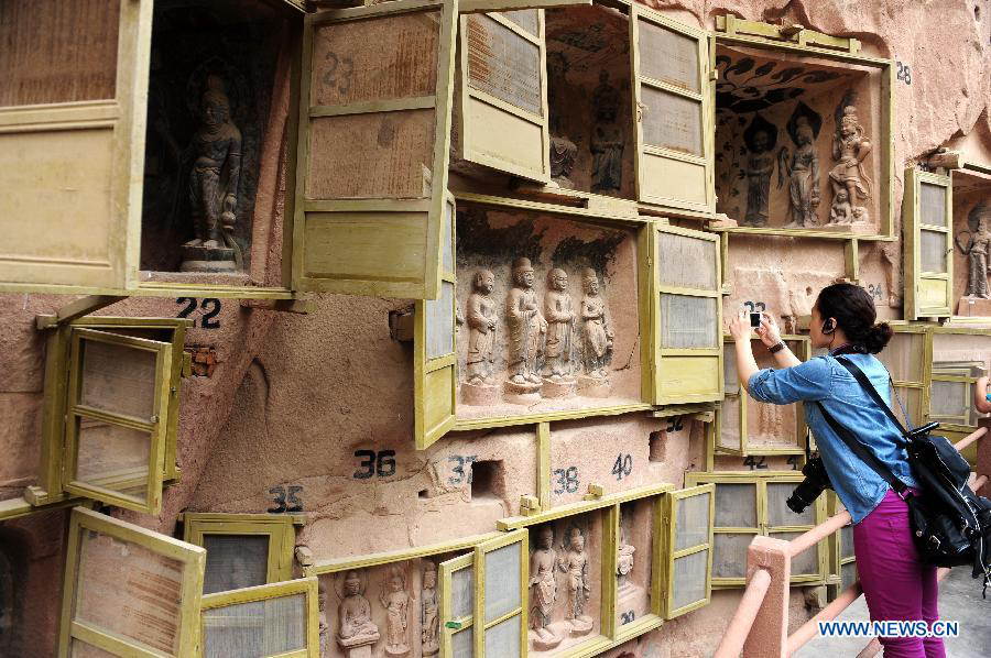 A tourist visits the Bingling Temple Grottoes in Yongjing County, northwest China's Gansu Province, July 17, 2013. Listed as part of the ancient Silk Road for the World Heritage candidate, the grottoes will be reviewed by experts from U.N. Educational, Scientific and Cultural Organization after renovation of a giant Buddha statue dating back more than 1,000 years to the Tang Dynasty was completed lately. Bingling Temple Grottoes, filled with Buddhist statues, stupas and murals, were a work in progress between the 4th and 10th centuries. (Xinhua/Nie Jianjiang)