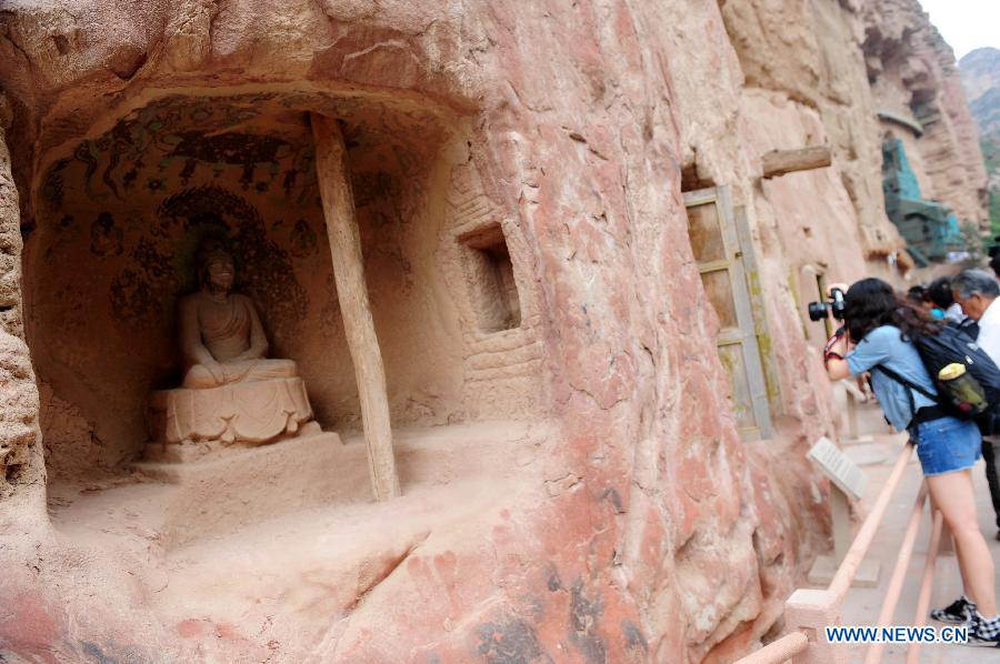Tourists visit the Bingling Temple Grottoes in Yongjing County, northwest China's Gansu Province, July 17, 2013. Listed as part of the ancient Silk Road for the World Heritage candidate, the grottoes will be reviewed by experts from U.N. Educational, Scientific and Cultural Organization after renovation of a giant Buddha statue dating back more than 1,000 years to the Tang Dynasty was completed lately. Bingling Temple Grottoes, filled with Buddhist statues, stupas and murals, were a work in progress between the 4th and 10th centuries. (Xinhua/Nie Jianjiang)