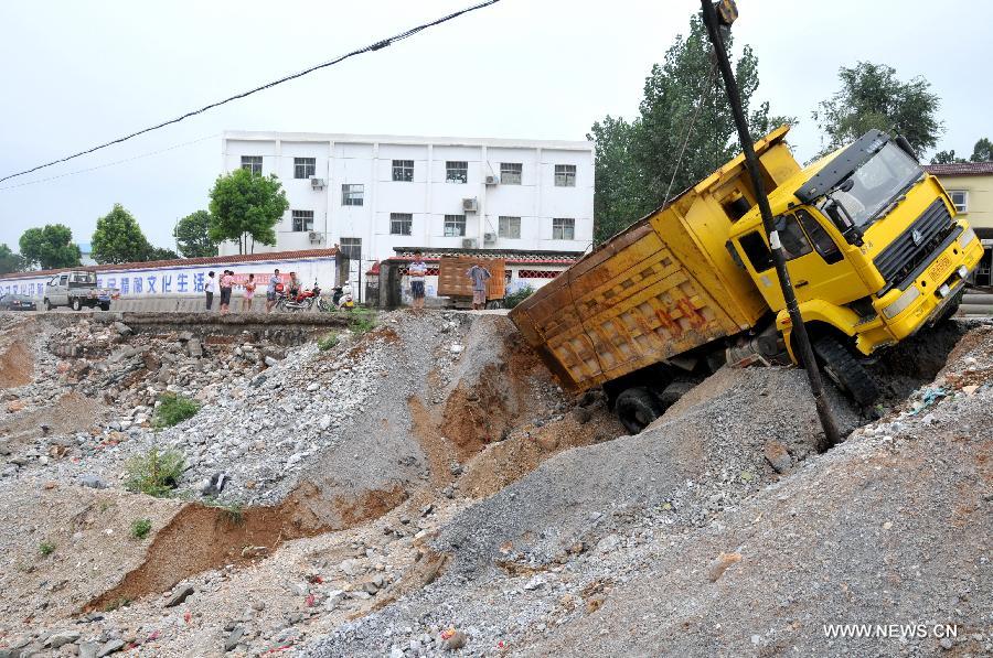 A truck is tossed off the road by flood caused by torrential rain in the Yangxi section of No. 209 national road in Yun County of Shiyan City, central China's Hubei Province, July 18, 2013. Four people were killed during heavy rainfall lasting from Wednesday evening to Thursday morning. (Xinhua/Cheng Fuhua)