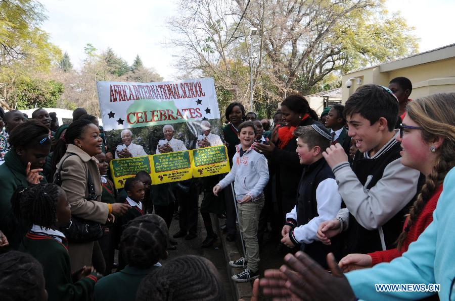 Students sing for Mandela outside his house in Johannesburg, South Africa, on July 18, 2013. South African former president Mandela is steadily improving, according to the Presidency website update released on Thursday. "Madiba remains in hospital in Pretoria but his doctors have confirmed that his health is steadily improving," said the statement. President Jacob Zuma wished the founding father of the nation a happy 95th birthday. (Xinhua/Guo Xinghua)