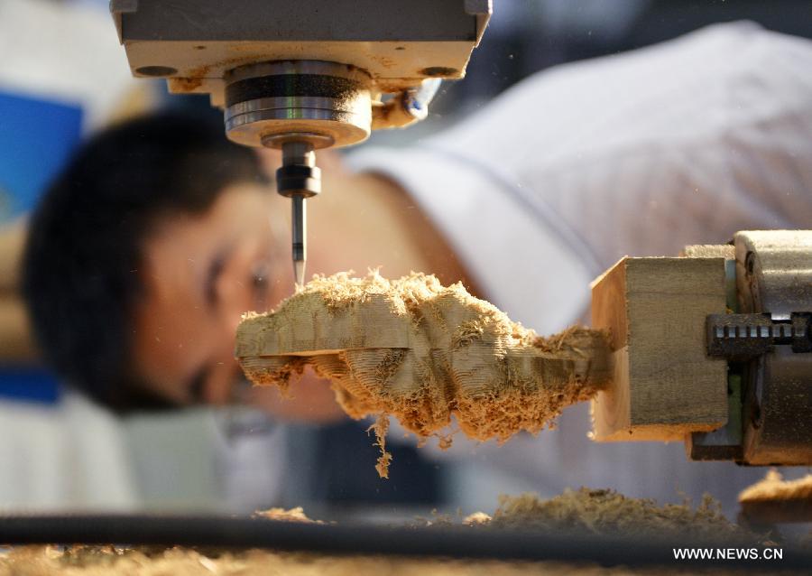 A man looks at a numerical control carving machine displayed at the 17th China West International Equipment Manufacturing Exposition (CWIEME) in Chengdu, capital of southwest China's Sichuan Province, July 18, 2013. The three-day CWIEME kicked off Thursday at Chengdu Century City New International Conference & Exhibition Center. (Xinhua/Hu Jiayan)