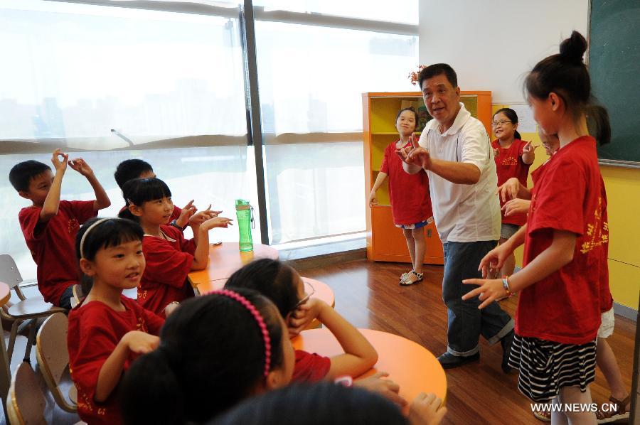 Zhang Liehu, a national first-class performer, guides children to experience Zuo, a performance of Peking Opera, in a youth and children's development center in Hangzhou, east China's Zhejiang Province, July 18, 2013. The lecture is held to enrich children's life during summer vacation.(Xinhua/Ju Huanzong)  