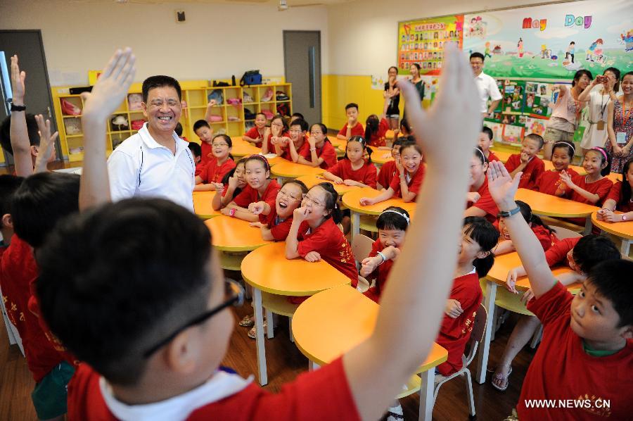 Zhang Liehu, a national first-class performer, guides children to experience Zuo, a performance of Peking Opera, in a youth and children's development center in Hangzhou, east China's Zhejiang Province, July 18, 2013. The lecture is held to enrich children's life during summer vacation.(Xinhua/Ju Huanzong) 