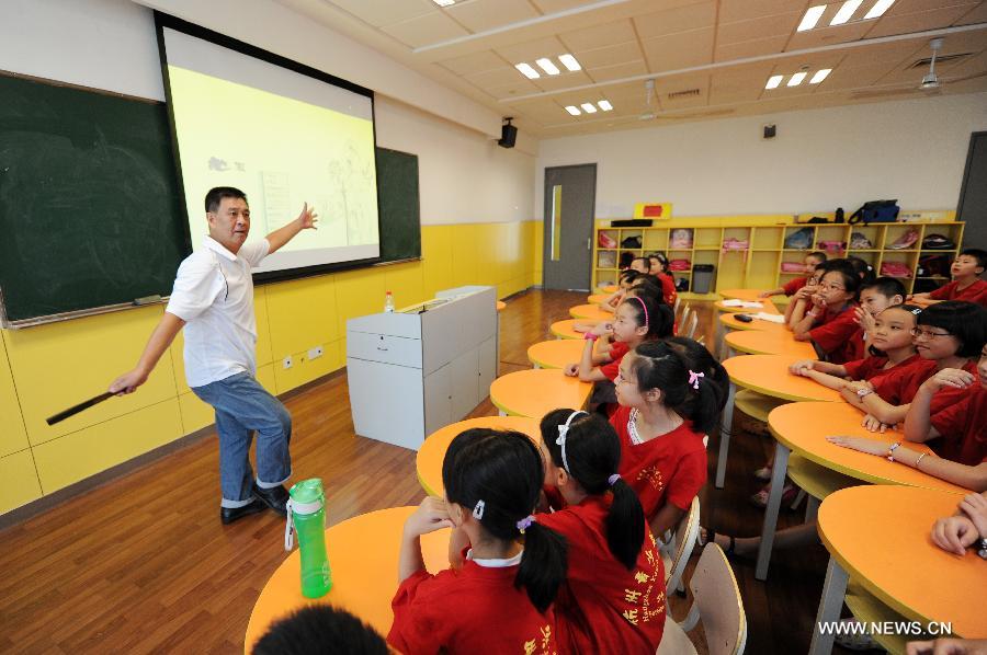 Zhang Liehu, a national first-class performer, shows basic skills of Peking Opera, at a lecture about Peking Opera in a youth and children's development center in Hangzhou, east China's Zhejiang Province, July 18, 2013. The lecture is held to enrich children's life during summer vacation.(Xinhua/Ju Huanzong)  
