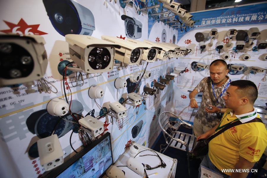 A staff member introduces surveillance cameras at the 2013 China International Exhibition on Public Safety and Security in Beijing, capital of China, July 18, 2013. The exhibition kicked off on Thursday at China International Exhibition Center. (Xinhua/Zhao Bing)
