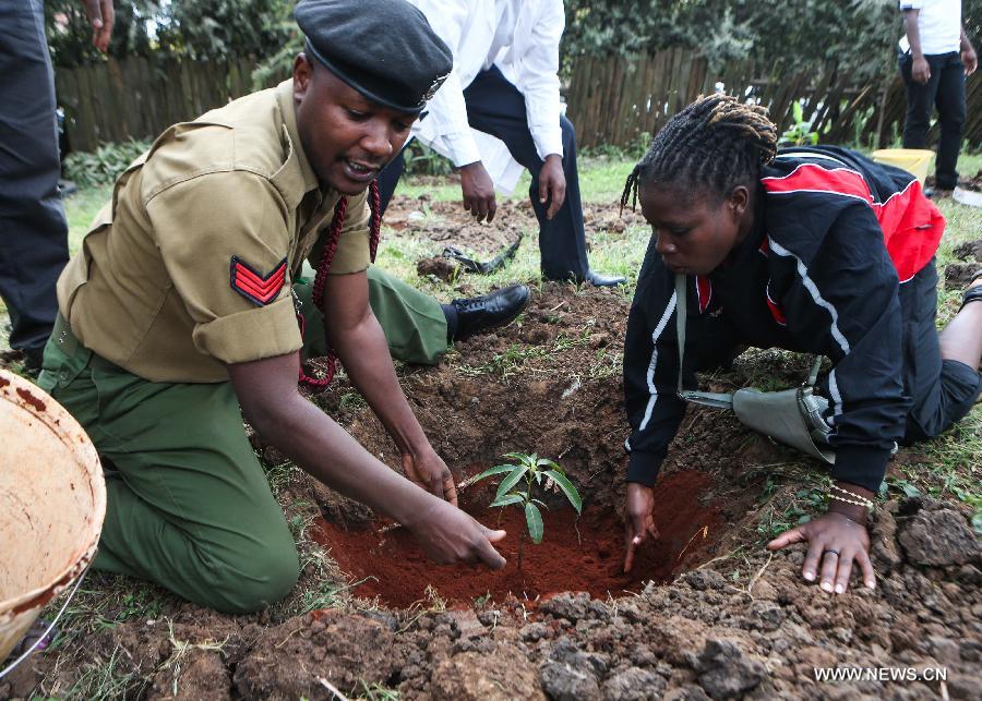 A policeman and a women from Kenya Rugby Union plant trees at Kilimani Primary School in Nairobi, capital of Kenya, July 18, 2013. A variety of activities, including tree planting, library wall painting and storytelling on Mandela's long walk to freedom, were held here on Thursday to celebrate Nelson Mandela Day. The theme for this year is "Take Action, Inspire Change and Make Every Day a Mandela Day." (Xinhua/Meng Chenguang)