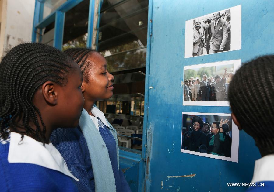 Two students look at Mandela's photos on the gate of an auditorium at Kilimani Primary School in Nairobi, capital of Kenya, July 18, 2013. A variety of activities, including tree planting, library wall painting and storytelling on Mandela's long walk to freedom, were held here on Thursday to celebrate Nelson Mandela Day. The theme for this year is "Take Action, Inspire Change and Make Every Day a Mandela Day." (Xinhua/Meng Chenguang)  