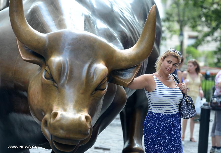 A woman poses for photos with the bronze bull in the Financial district which has become a Wall Street icon in New York City, July 18, 2013. U.S. stocks continued to rise on Thursday, sending the Dow Jones Industrial Average and the S&P 500 to fresh all-time highs, boosted by upbeat economic data and corporate earnings. (Xinhua/Wang Lei) 