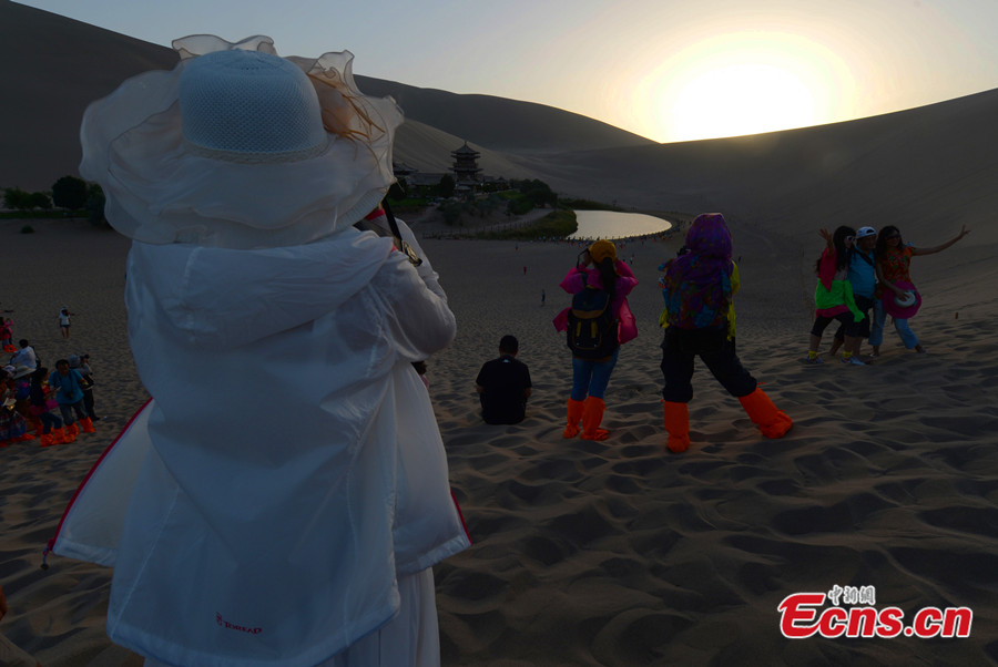 Visitors take sunset photos at the scenic spot of Crescent Lake in Dunhuang City of Northwest China's Gansu Province. (CNS/Jia Guorong)