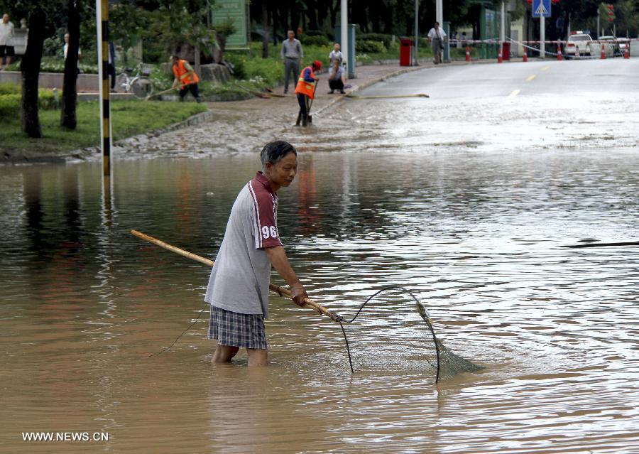 A resident fishes in a flooded street in Guangyuan City of southwest China's Sichuan Province, July 18, 2013. A rain-triggered flood has brought serious damage to Guangyuan City from Wednesday, causing one person missing and forcing 41,400 people to relocate. (Xinhua/Gao Zhinong)